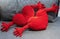 Two red plush pillows in the shape of hearts with hands on a gray sofa