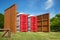 Two red portable restrooms in a park