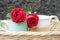 Two red roses and couple cup of tea or coffee in a wooden rattan basket on blue background. Relationship and valentine day concept