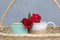 Two red roses on couple cups of tea or coffee in a wooden rattan basket on blue background. Relationship and valentine day concept