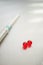 Two red round capsules on a metal chrome table. Syringe on blurred background. Treatment and recovery