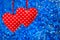 Two red sewn hearts hanging against blue background