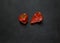 Two red shriveled peppers on a black stone surface. top view with space, horizontally