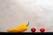 Two red small tomatoes and one large yellow pepper lie in a row on the board