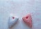 Two red and white fabric hearts on a pink marbled paper background