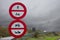 Two red and white prohibition signs on the highway in rainy weather.