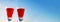 Two red wineglasses on the blue sky background in a sunny day. Banner. Copy space