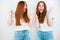 Two redheaded young women both looking happy expressing positive emotions standing on isolated white backgroung, body language