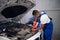 Two repairmen repair a damaged car engine