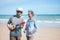 Two retired Asian couples play guitar and dance happily on the beach during their leisure time