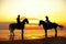 Two riders on horseback at sunset on the beach. Lovers ride horseback. Young beautiful man and woman with a horse at the sea. Rom