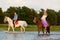 Two riders on horseback at sunset on the beach. Lovers ride horseback. Young beautiful man and woman with a horses at the sea.