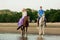 Two riders on horseback at sunset on the beach. Lovers ride horseback. Young beautiful man and woman with a horses at the sea.