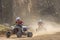 Two riders on a quad bike in the dust race