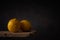 Two ripe lemons lie side by side on old boards against a dark backdrop. moody artistic still life with copy space