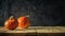 Two ripe orange pumpkins on rough boards against a background of black concrete plaster in a semi-darkness with copy space