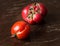 Two ripe ugly trendy tomatoes on a brown background. One tomato cracked