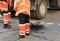 Two road builders assemble and level fresh asphalt with a shovel and level on the repaired part of the road