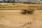 Two road construction workers in orange vests and protective helmets in the middle on the field