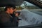 Two robbers sitting inside a car with guns looking at the blueprint of the building