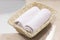 Two rolled white hand towels in light rectangular basket on the