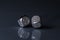 Two Rolling Silver Casino Dice on Black Background with blue bottom