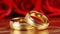 Two romantic red gold wedding rings against vibrant red roses and soft bokeh lighting