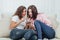 Two roommates using their smartphones at home sitting on a sofa in the living room.