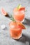 Two rosemary grapefruit sodas on light grey. Vertical format