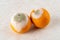 Two rotten oranges covered with white green mold on a kitchen table. Fungal mold on rotten citrus. Spoiled fruits and vegetables.