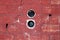 Two round electrical outlet boxes without wires mounted inside dilapidated red brick wall