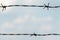 Two rows of barbed wire against a blue sky. Protection of life and property. Protection of criminals in prison. Peaceful sky