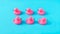 Two rows of neatly aligned pink plastic ducks against blue background. Minimal creative concept for summer holidays banner or