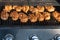 Two rows of tasty just grilled chicken breasts on grilling grid, meat covered by sauce and species