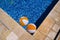 Two rubber air yellow white inflatable balls and toy for swimming pool in transparent blue water. Beach balls floating on water.
