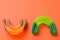 Two rubber tooth and lip protections, orange and green, for boxing or karate, on a blue background, concept