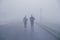 Two runner athletes running along the road for training in foggy weather Blurred