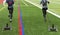 Two runners pulling sleds with weights on a turf field