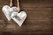 Two rustic metal heart ornaments hanging on wood