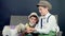 Two rustic, stylishly dressed boys play with ducklings, chickens, and a small dog. In the background a haystack, colored