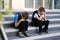 Two sad boys, schoolchildren in black clothes are sitting on the steps of the porch of a building, covering their faces, the