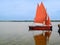 Two sailing dinghies with red sails