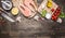 Two salmon steak on paper with pepper, herbs, a knife and fork, butter, herbs, cherry tomatoes on wooden rustic background top vie