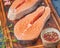 Two salmon steaks, fish fillet, large sliced portions  on a chopping board on dark table. Food background