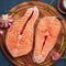 Two salmon steaks, fish fillet, large sliced portions  on chopping board on a dark table. Top view, close up