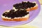 Two sandwiches with black sturgeon caviar on purple plate yello