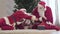 Two Santa Clauses in red costumes fighting for Christmas bag indoors. Caucasian men pulling gifts sack. New Year