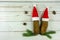 Two santa hats on pine cones layout on white wooden background symbol of togetherness at christmas