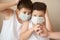 Two scared boys in medical mask looking at hand with syringe