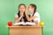 Two school girl sharing secrets sitting at a desk from book
